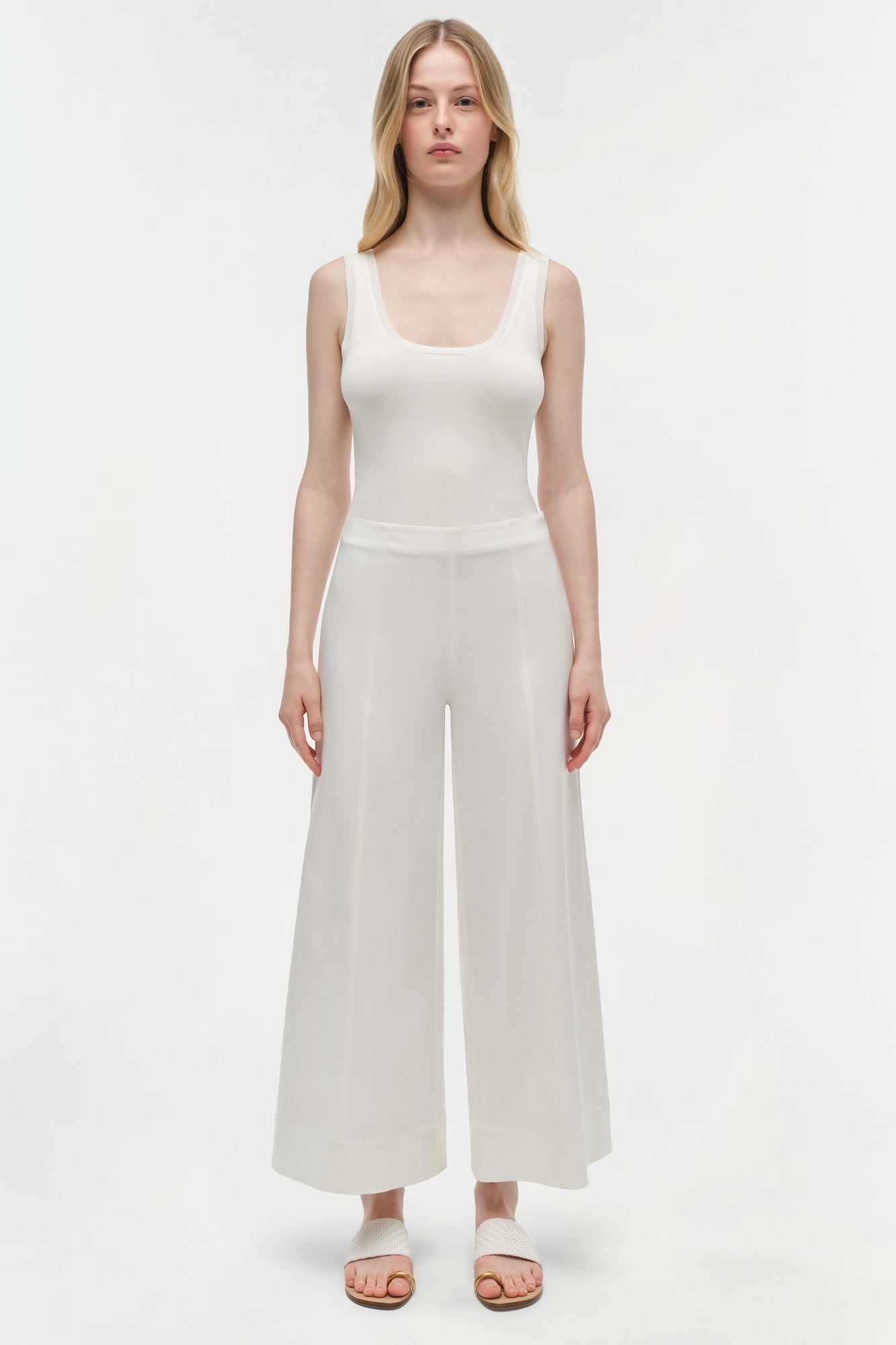 Woman wearing a white sleeveless tank top and off-white cotton cropped pants with a wide-leg silhouette.