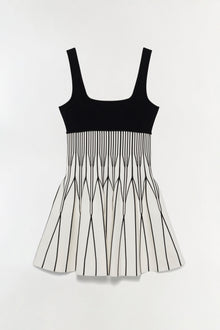 Black and white knit mini dress with solid black bodice and pleated skirt with vertical stripe pattern.