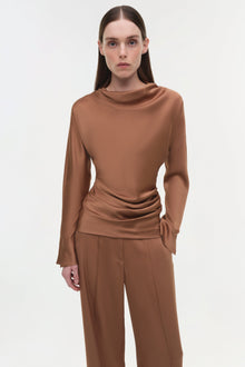 Woman wearing tan satin wide-leg pants with a matching long-sleeve draped top.