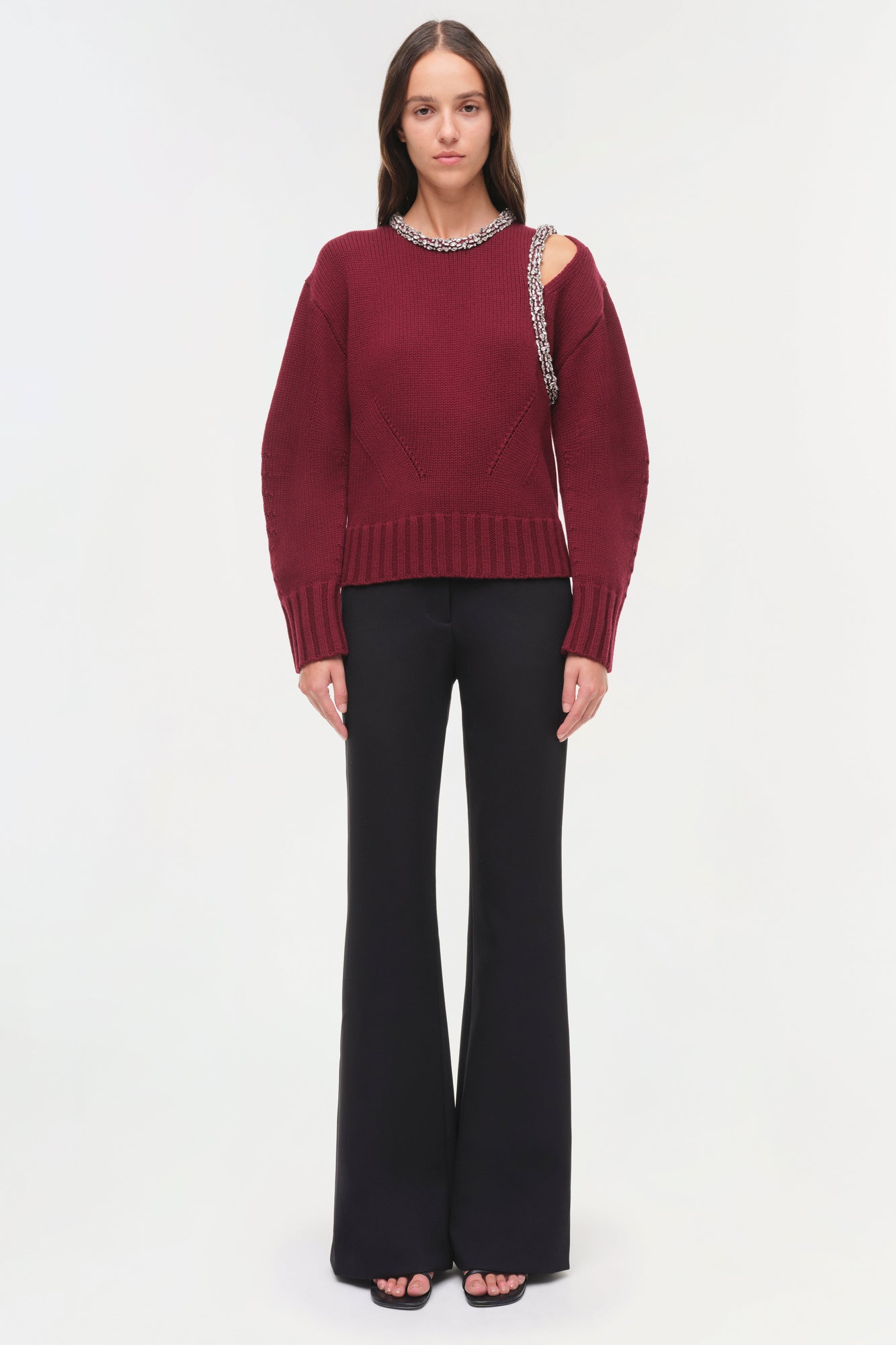 Burgundy ribbed pullover with jeweled neckline and cutout shoulder detail, paired with black flare pants.