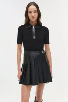 Black mini dress with ribbed knit short-sleeve top, leather collar, half-zip closure, and pleated leather skirt with belt.