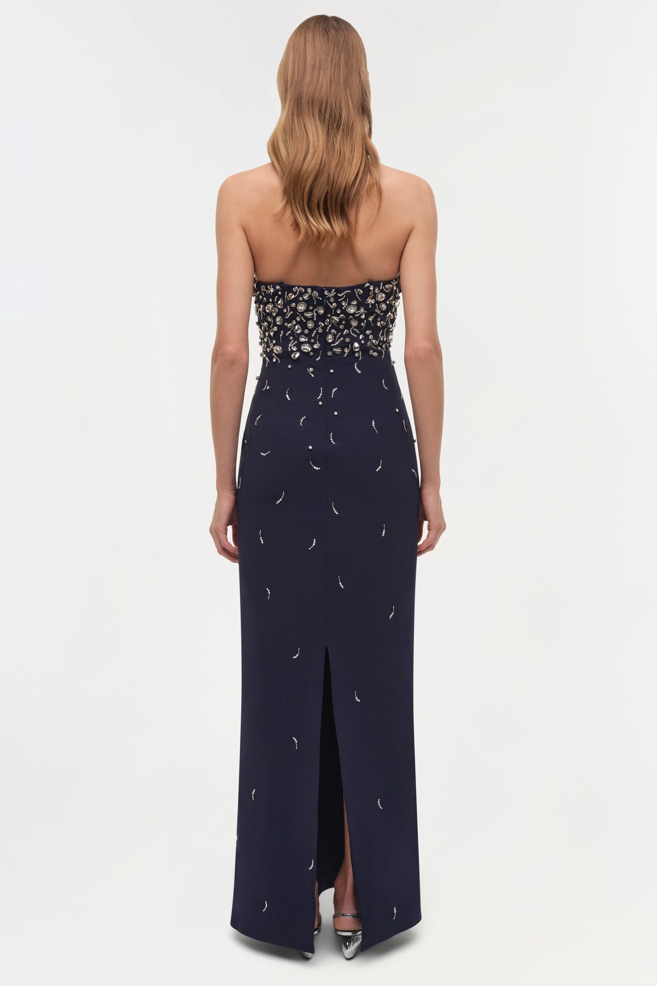 Navy strapless gown with crystal embellishments on bodice and crescent moon beading throughout skirt, featuring a front slit.
