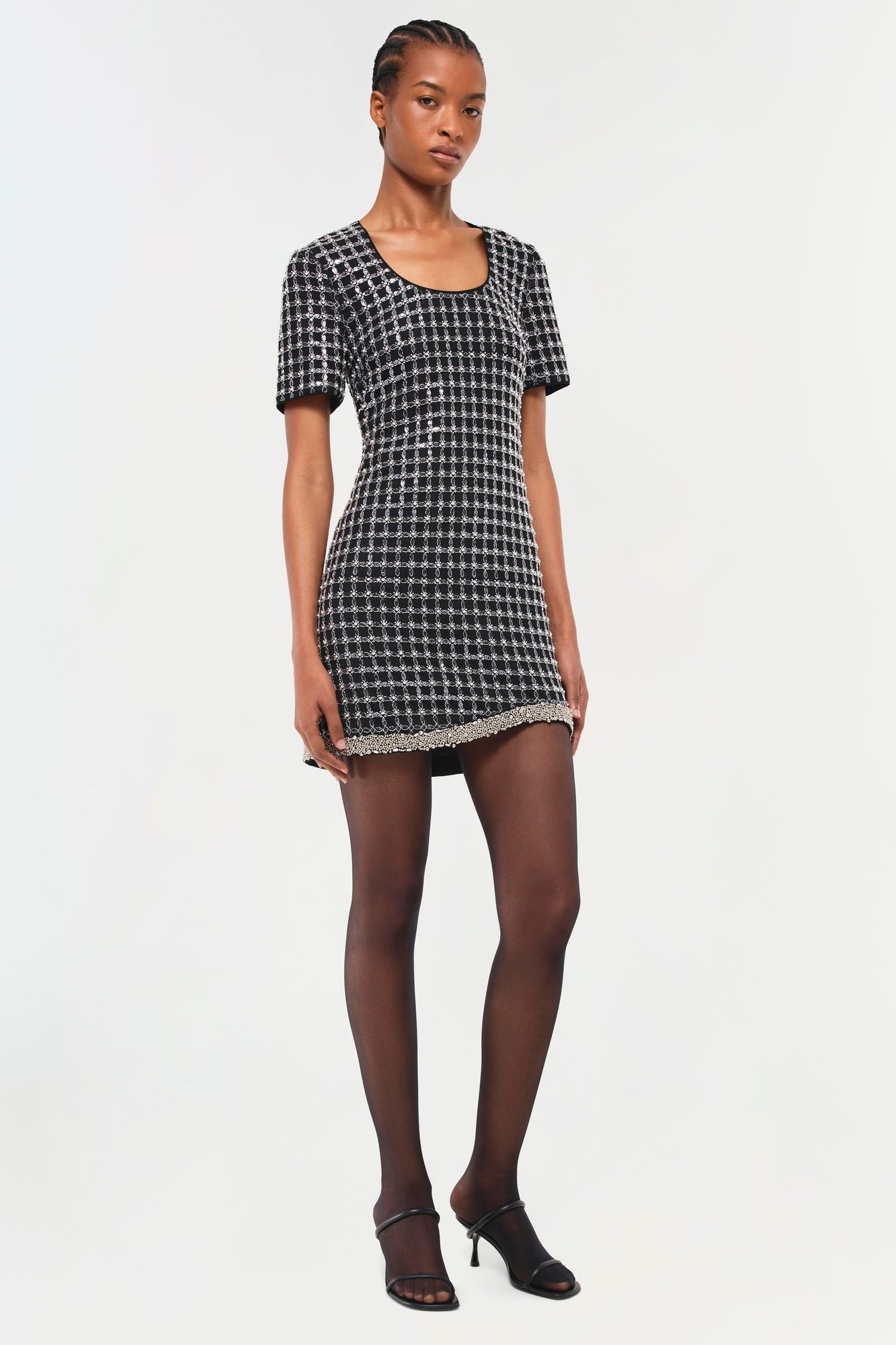 Black and white houndstooth mini dress with short sleeves and embellished trim at hem.