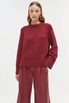 Burgundy crewneck cashmere sweater with ribbed cuffs and hem on model wearing matching pants.