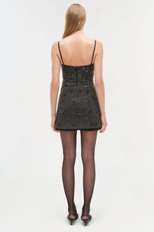 Black sequined mini dress with spaghetti straps and open back, worn with black tights and heels.
