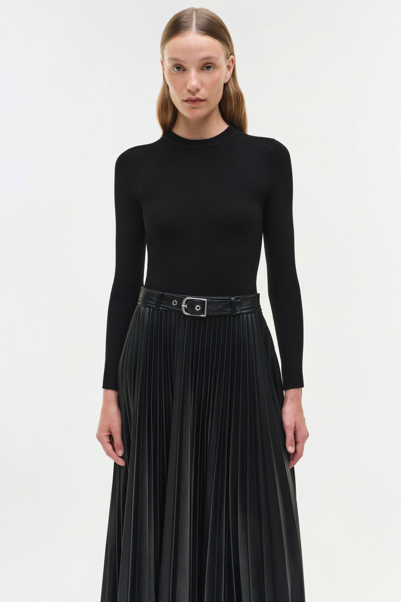 Black knit midi dress with long sleeves, pleated skirt, and belted waist.