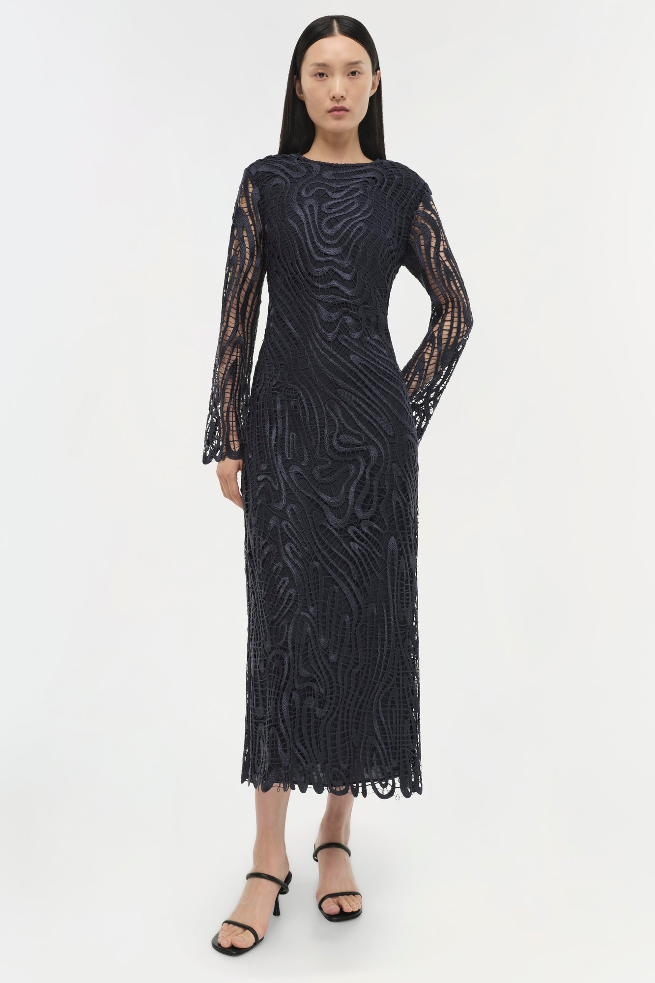 Black lace midi dress with long sleeved crochet sleeves and wavy pattern throughout.