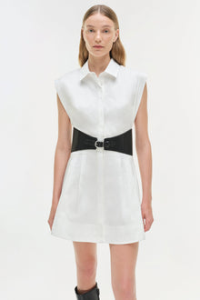 White cotton shirt dress with black bow belt at waist and button-front closure.