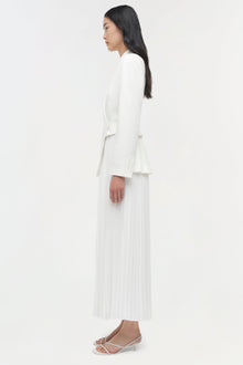 White blazer midi dress with pleated skirt and long sleeves on model wearing white sandals.
