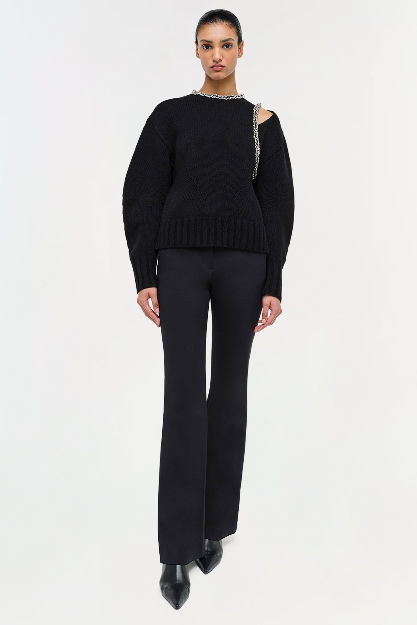 Black ribbed pullover with silver chain embellishments at neckline and shoulder cutout.