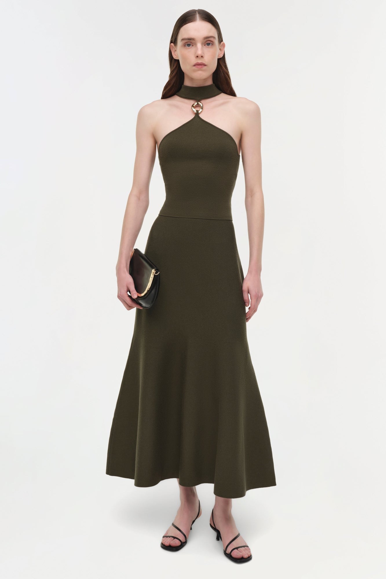 Olive green wool midi skirt with A-line silhouette and high waistband, shown on model wearing black strappy sandals.