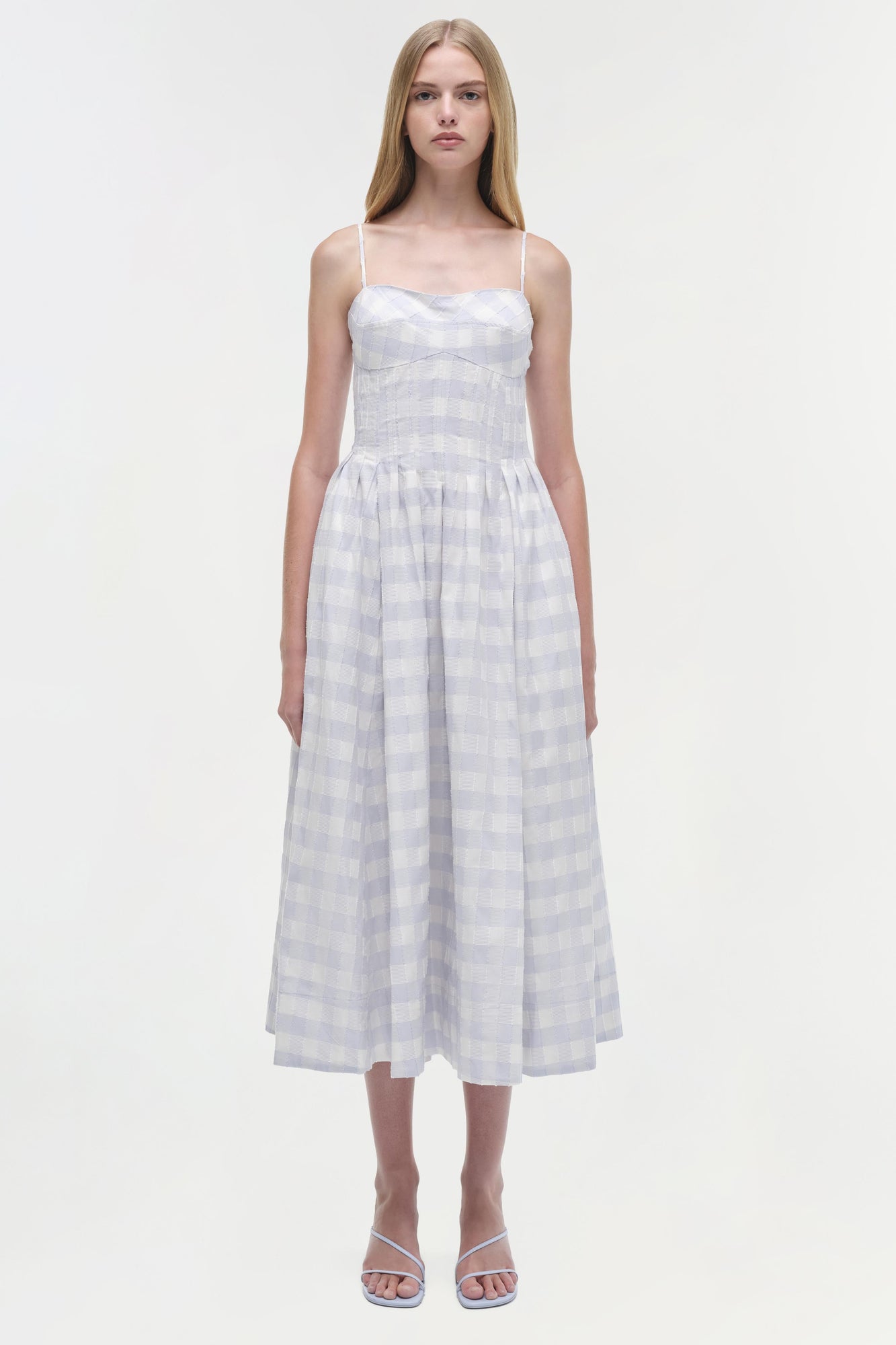 Light lavender gingham cotton midi dress with thin straps and fitted bodice worn with white sandals.