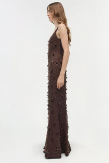 Brown sleeveless floor-length gown with beaded and fringe embellishments throughout, shown on model in profile.