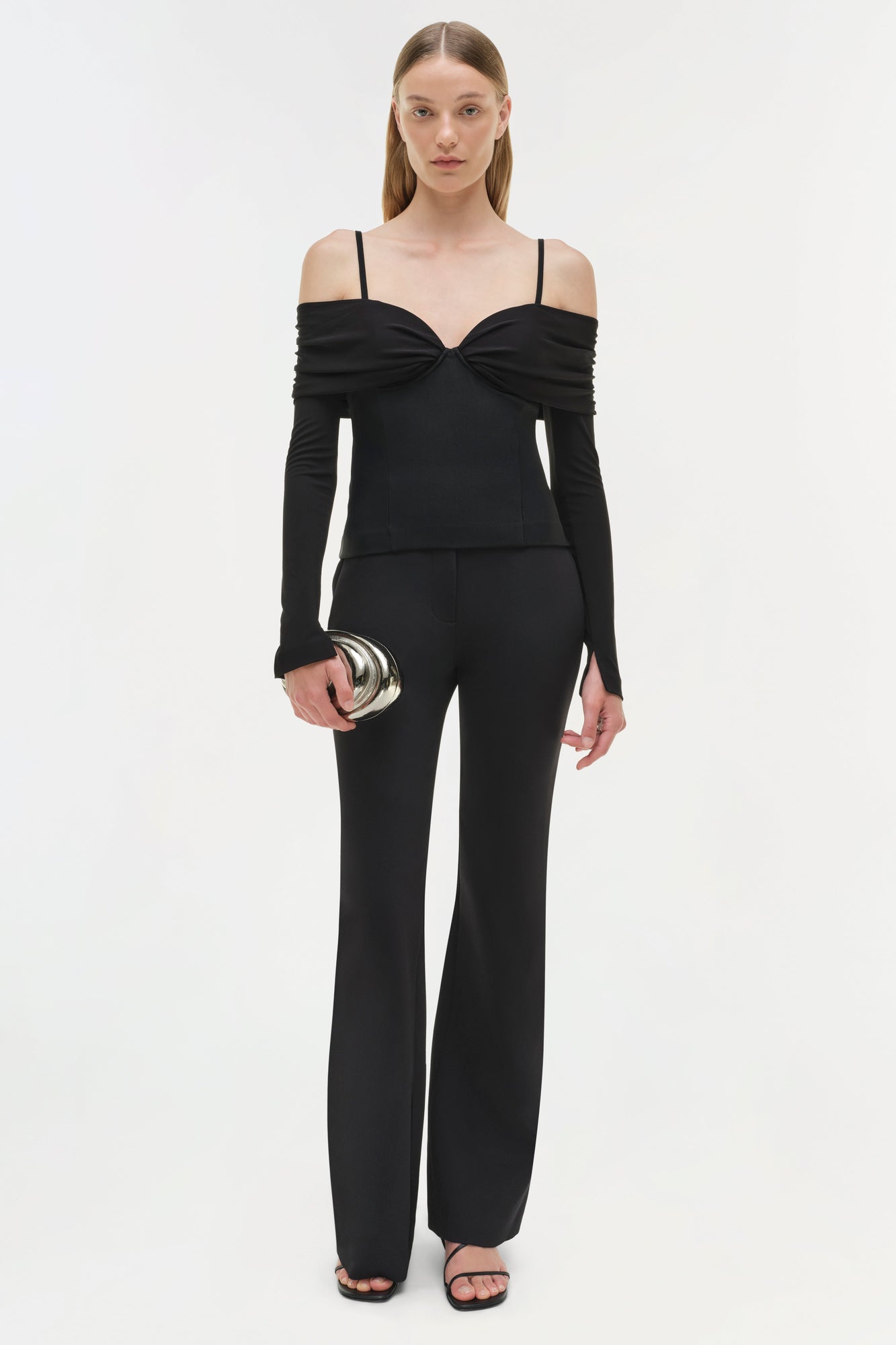 Black off-shoulder top with long sleeves, twist front detail, and thin shoulder straps on model.