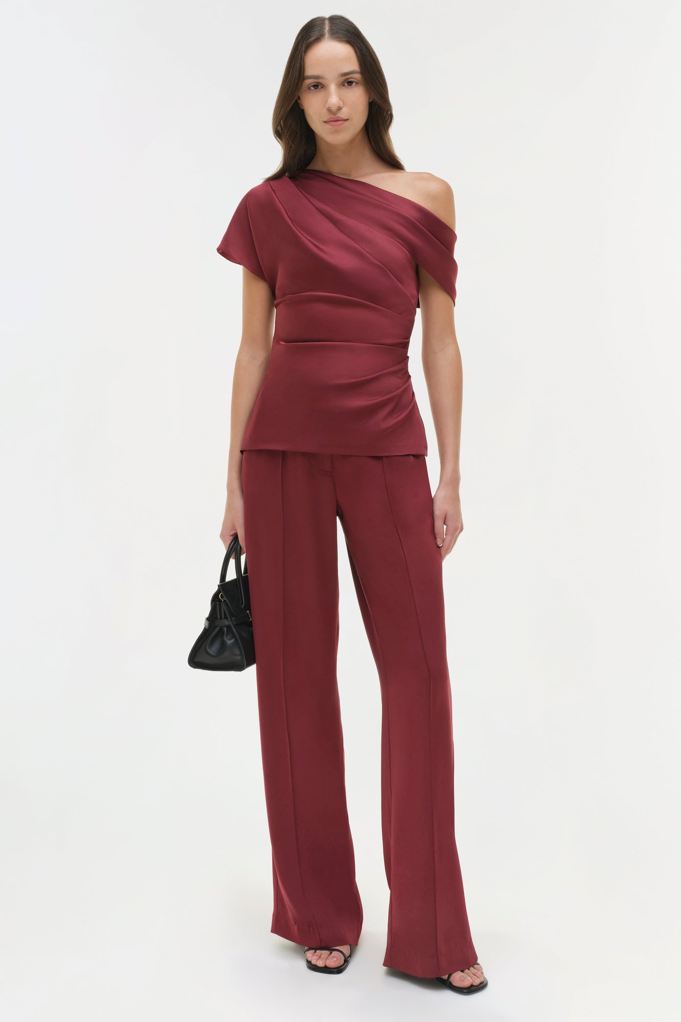 Burgundy draped satin top with asymmetrical neckline and short sleeves worn with matching wide-leg pants.