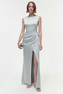 Light gray sleeveless gown with draped waist and high slit, shown on model wearing silver clutch.