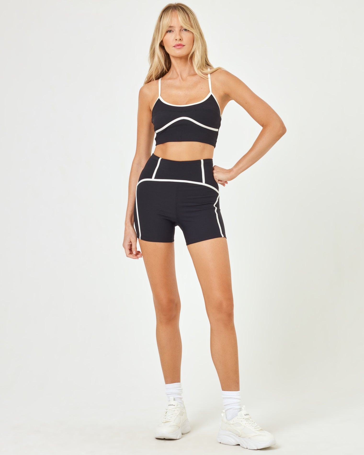 Front view of model wearing the Revel Top in black-cream with matching black-cream Revel Short and white sneakers.
