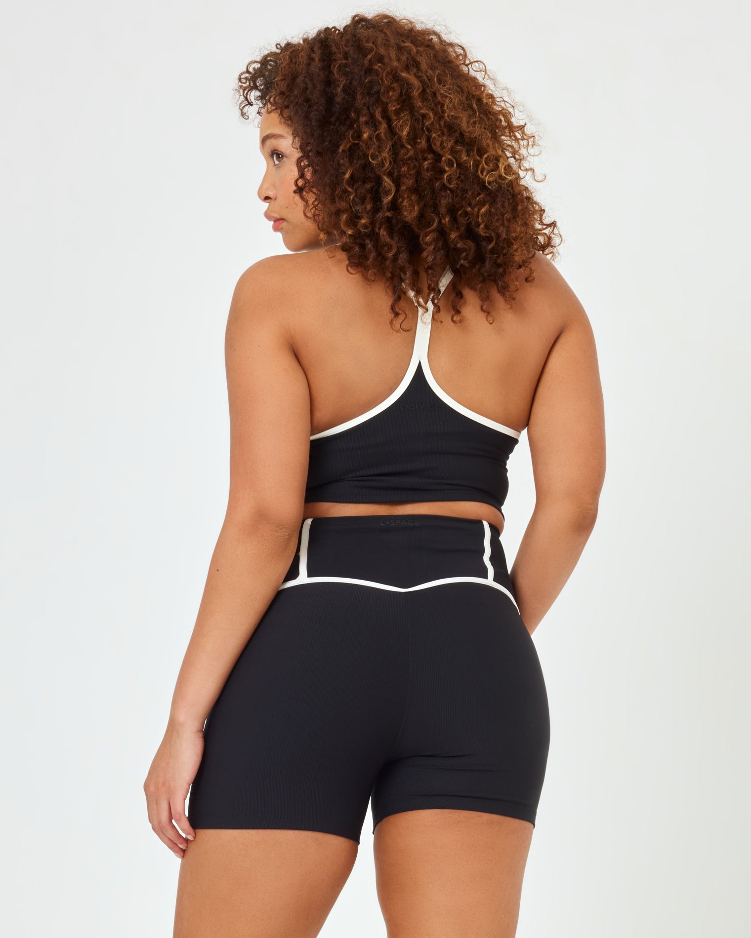 Back view of model wearing XL in the Revel Short in black-cream showing the cream piping on the waistband, with matching black-cream Revel Top.
