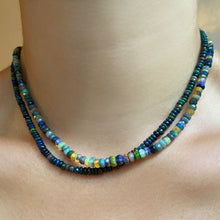 Shimmering beaded necklace made of smooth opal rondels in shades of black, navy, and green on a slim gold lobster clasp.