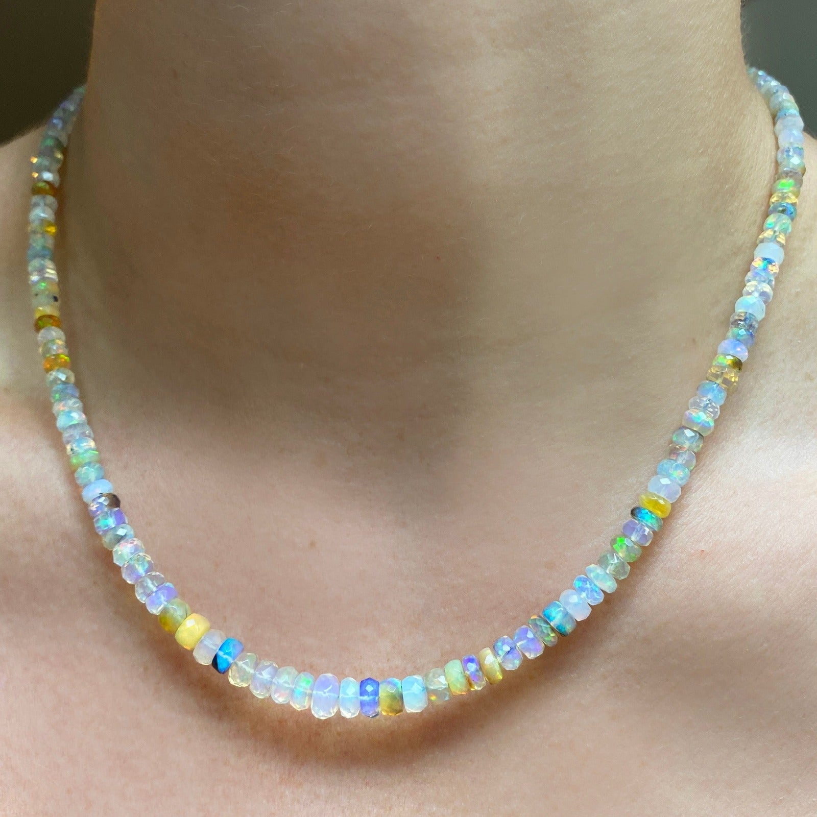 Shimmering beaded necklace made of faceted opals in shades of white, clear, and yellow on a gold linking ovals clasp. 