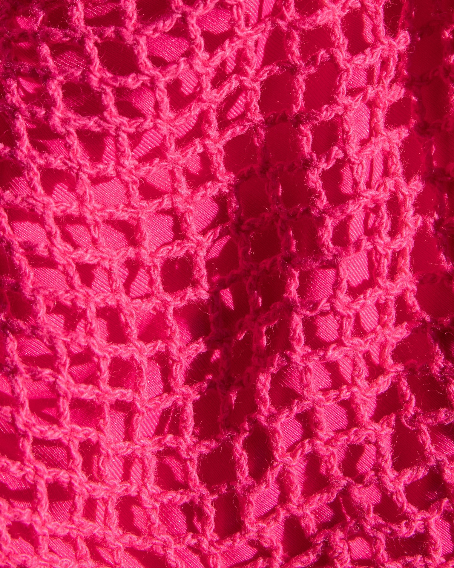 Close-up of a textured pink fabric with a crochet pattern