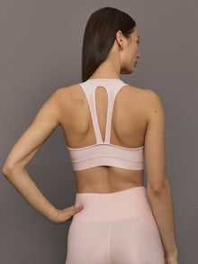 Model wears a v neck baby pink bra in a liquidy takara shine finish. 