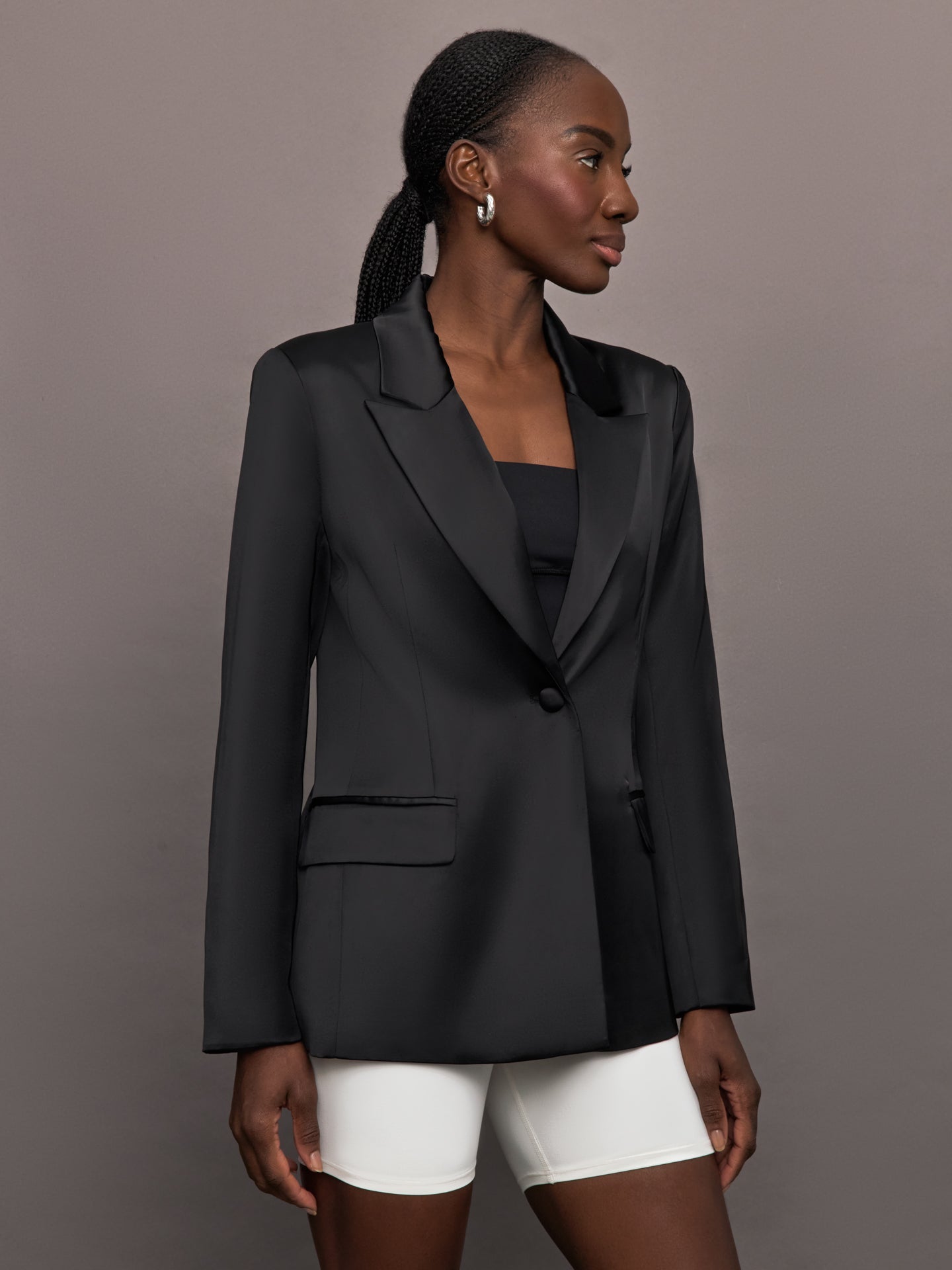 Model wears a black satin single breasted blazer. 