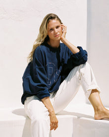 Lifestyle editorial shot of a model wearing the LSPACE Legend Sweatshirt in midnight blue, in a different styled outdoor setting.