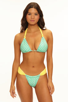 Woman wearing a green and yellow bikini with a white background