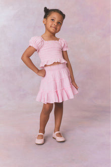 Pink gingham cotton off the shoulder top with puff sleeves and a smocked bodice flowing to a peplum finish for girls.