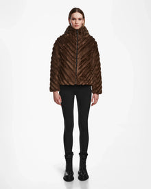 A person faces forward, wearing the Rudsak ANASTASIA - 8124804 Espresso dark brown winter jacket, paired with black leggings and black lace-up boots, set against a plain white background.