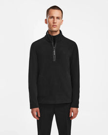 A man with short hair and a neutral expression models the Rudsak BECK - 6524538 Black men’s fleece half-zip pullover with front pockets and vegan leather trims, set against a plain white background, ideal for casual wear.