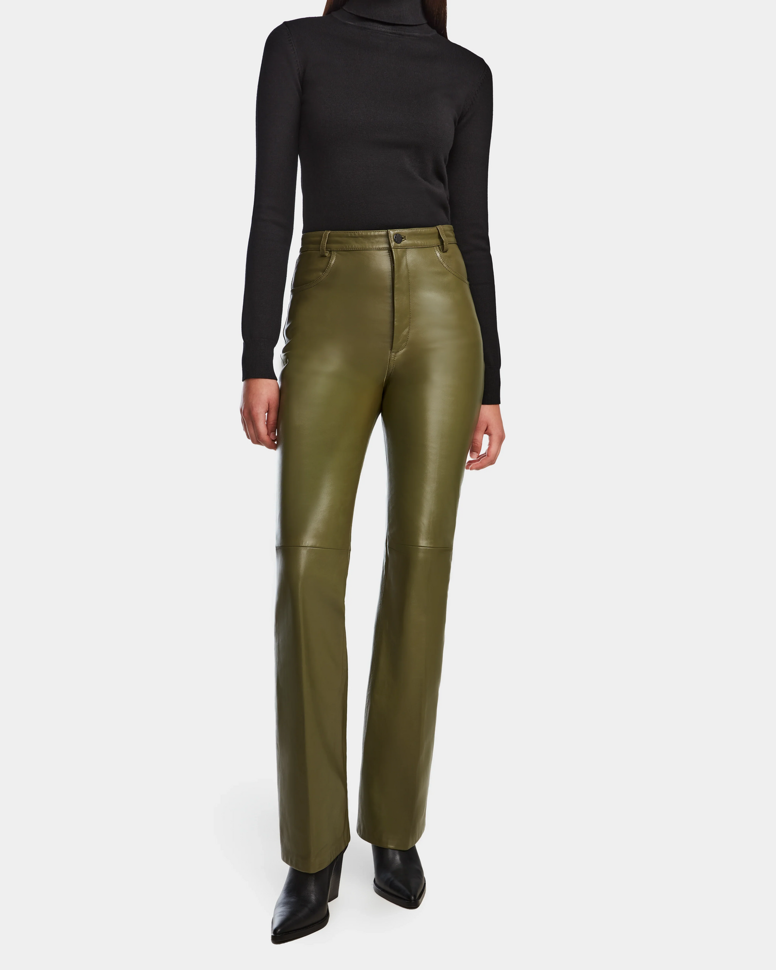 A person stands against a plain white background wearing Rudsak’s CARISSA - 8524545 Loden Green high-waisted pants with a fitted black turtleneck and black pointed-toe shoes; their face is not visible.