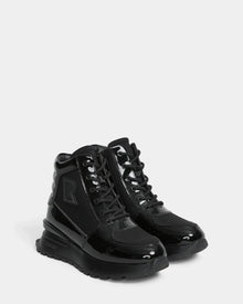 The CHELSA - L224505 Black by Rudsak are women’s sneaker boots with shiny patent leather accents, thick rubber soles, black laces, and side branding—offering a stylish upgrade to classic winter boots. Displayed on a plain white background.