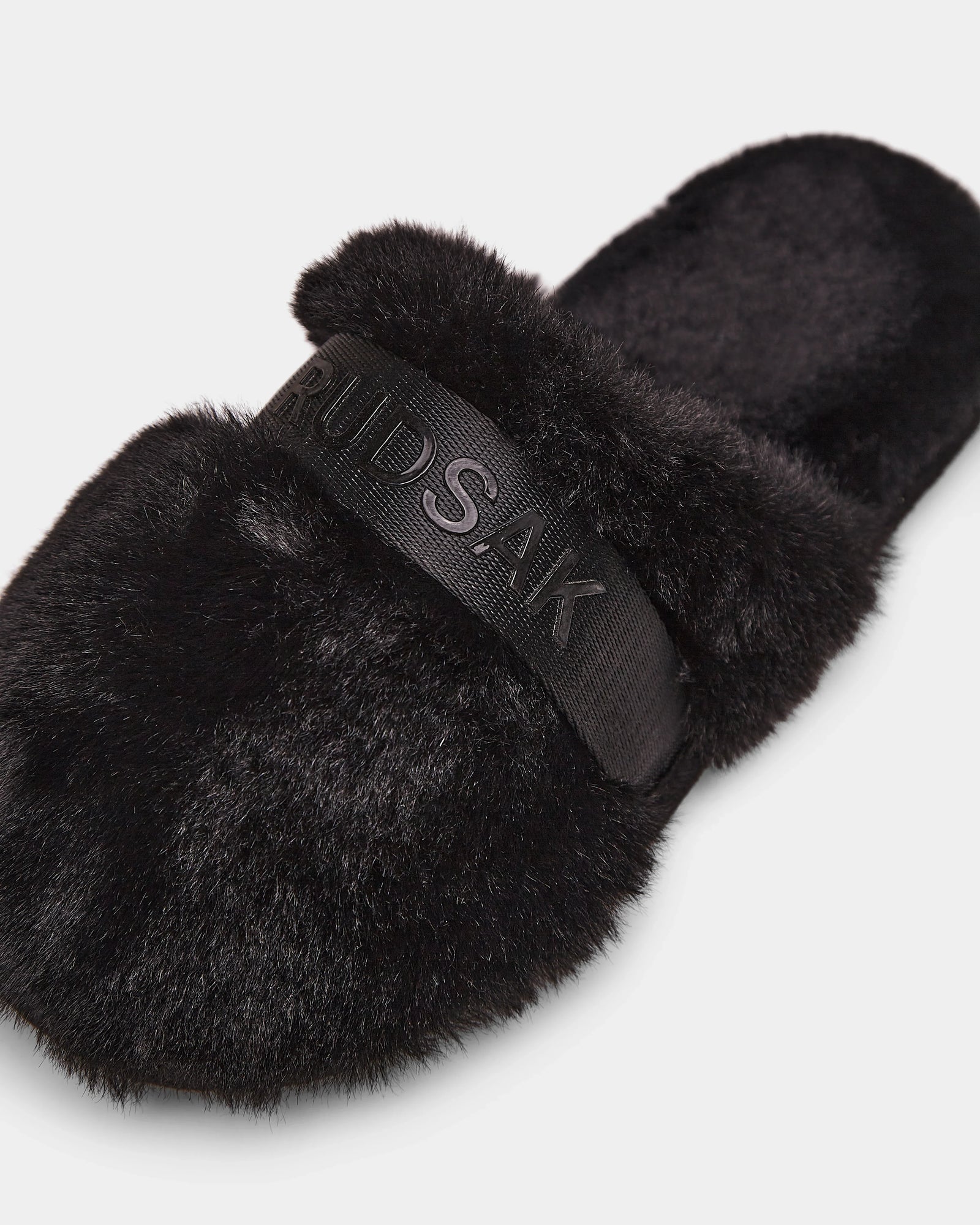 The FLUFF - L223509 Black by Rudsak is a cozy women's slipper with a wide, embossed strap, black faux-fur texture, and open back—perfect lounge footwear for comfort.