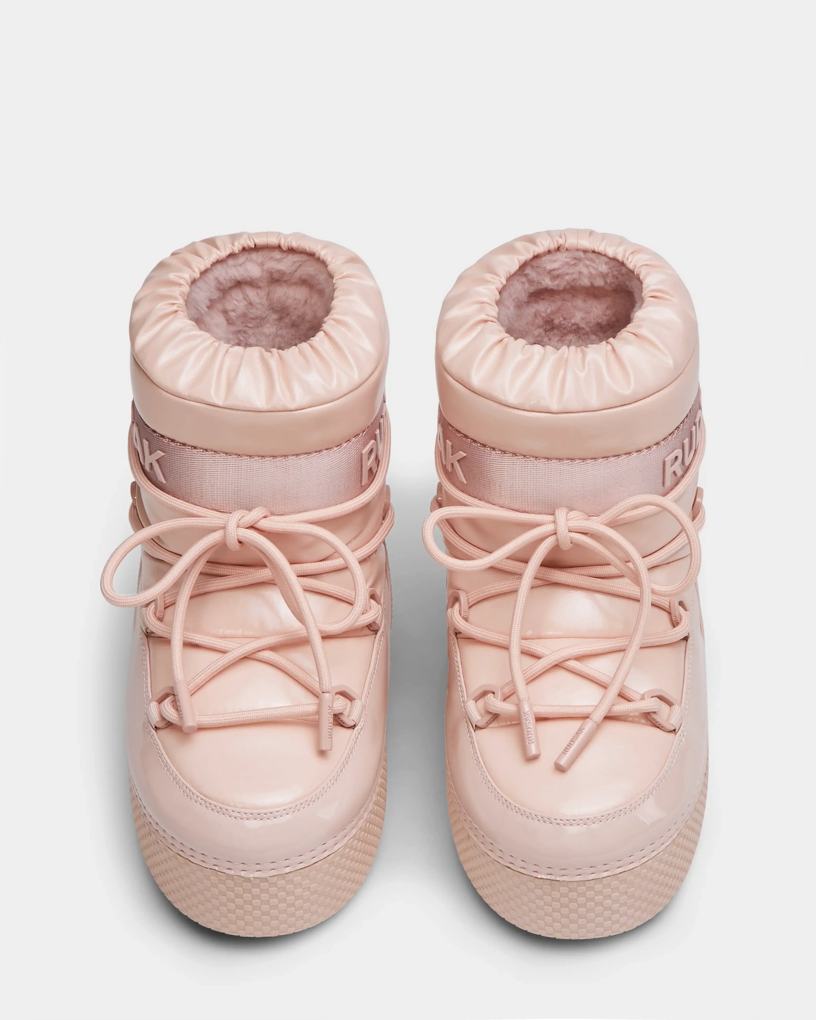 The HARLOW Y - 1223500 Pastel Pink kids boots by Rudsak feature light pink, fur lining, round toes, crisscross laces, rubber soles, and a thick ankle band—ideal weather-resistant footwear for winter adventures.