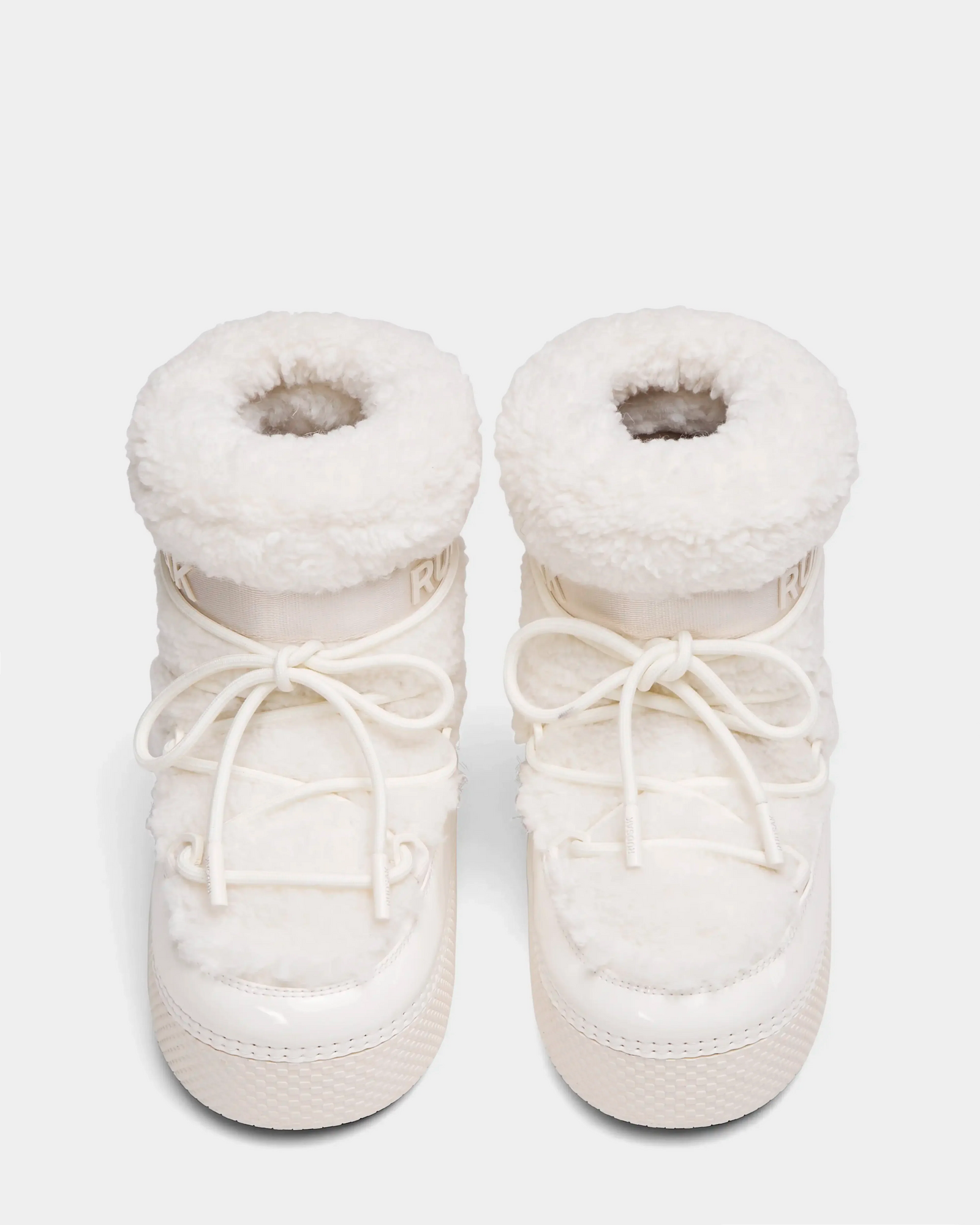 The Rudsak KATHY Y - 1224500 Iceland boots are white, furry winter boots with thick soles, round toes, front laces, and a plush sherpa-like finish. Water-repellent moon boots shown side by side on a white background.