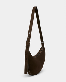 The LANISSA S - 8324520 Espresso by Rudsak is a dark brown suede crescent-shaped hobo bag with a wide adjustable strap and zipper closure, styled as a minimalist women’s crossbody against a light background.