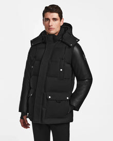 A man wearing the Rudsak RICKY R - M123506 Black parka with recycled leather sleeves and multiple pockets stands against a plain white background.