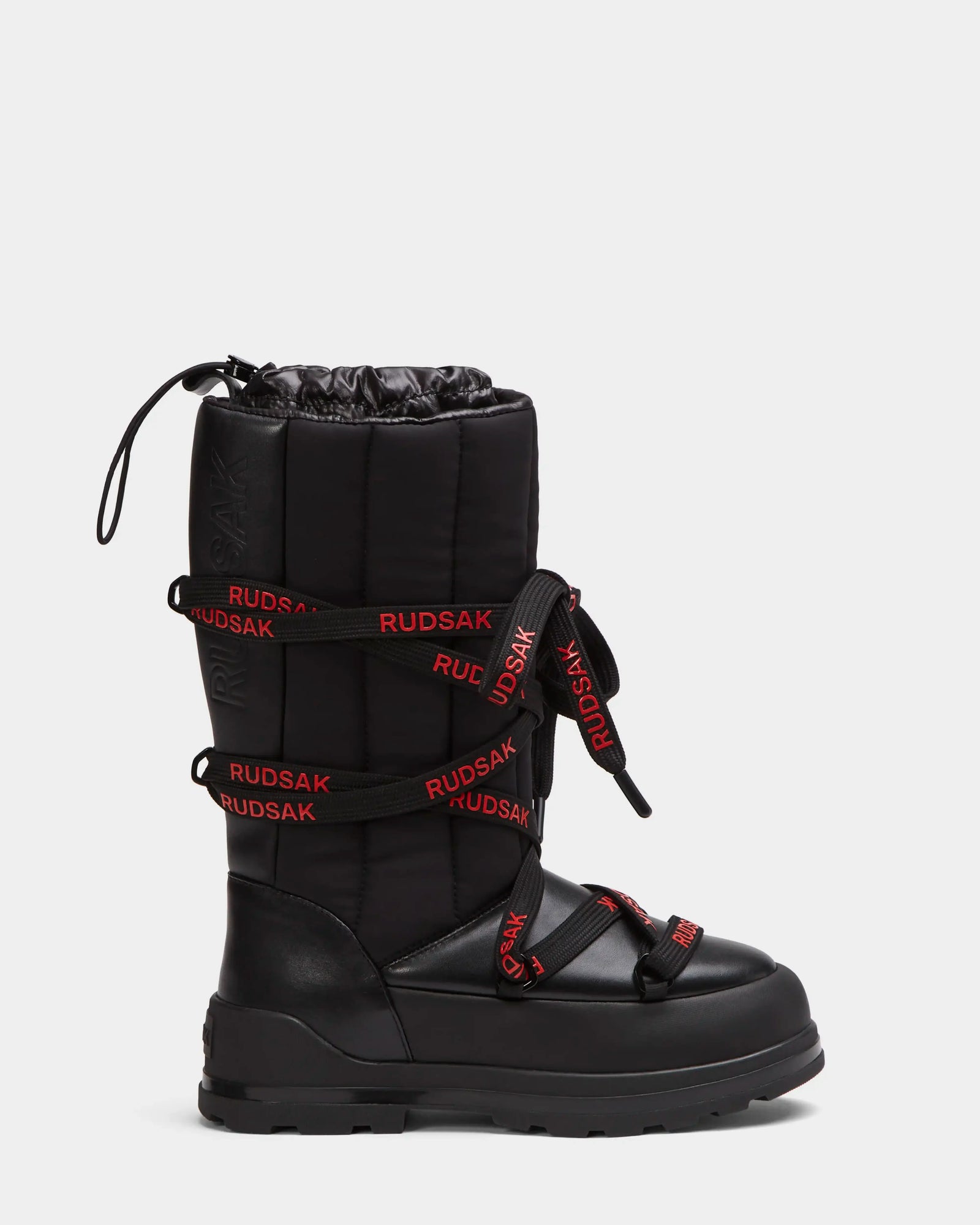 The RODIN - 8224502 Black by Rudsak is a women’s mid-calf winter boot featuring a thick padded shaft, polar fleece lining, black anti-slip sole, red laces with RUDSAK, and a drawstring closure for warmth and stability.