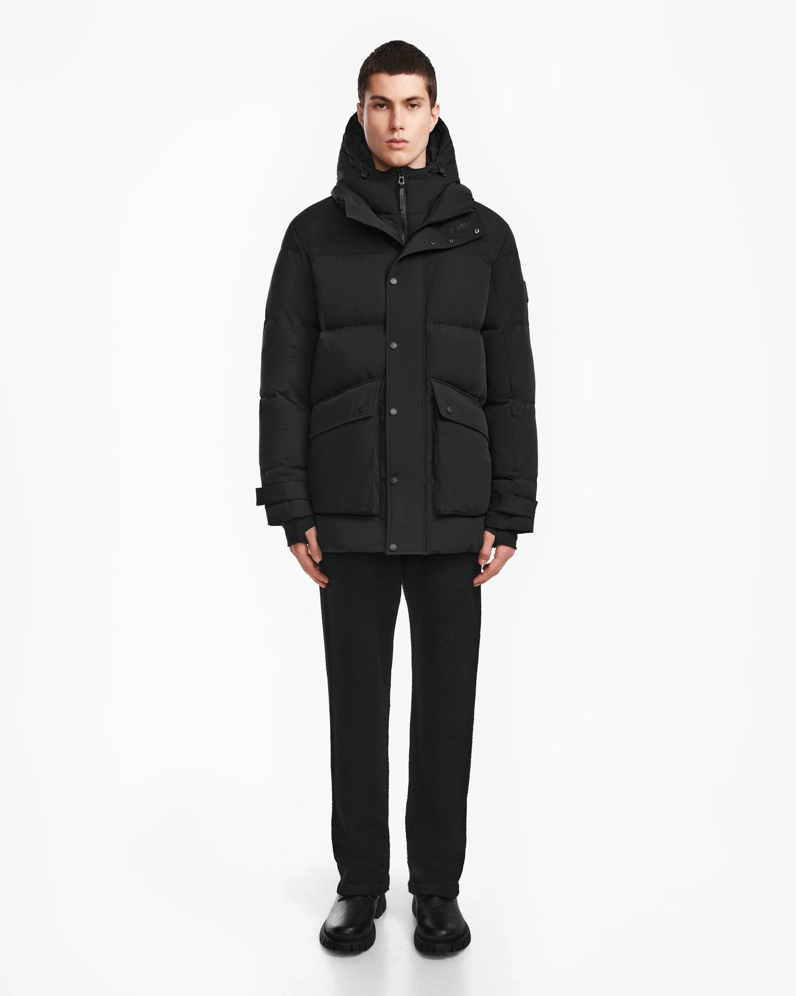 A man wearing the Rudsak ROKO - 6124510 Black mens quilted down parka.