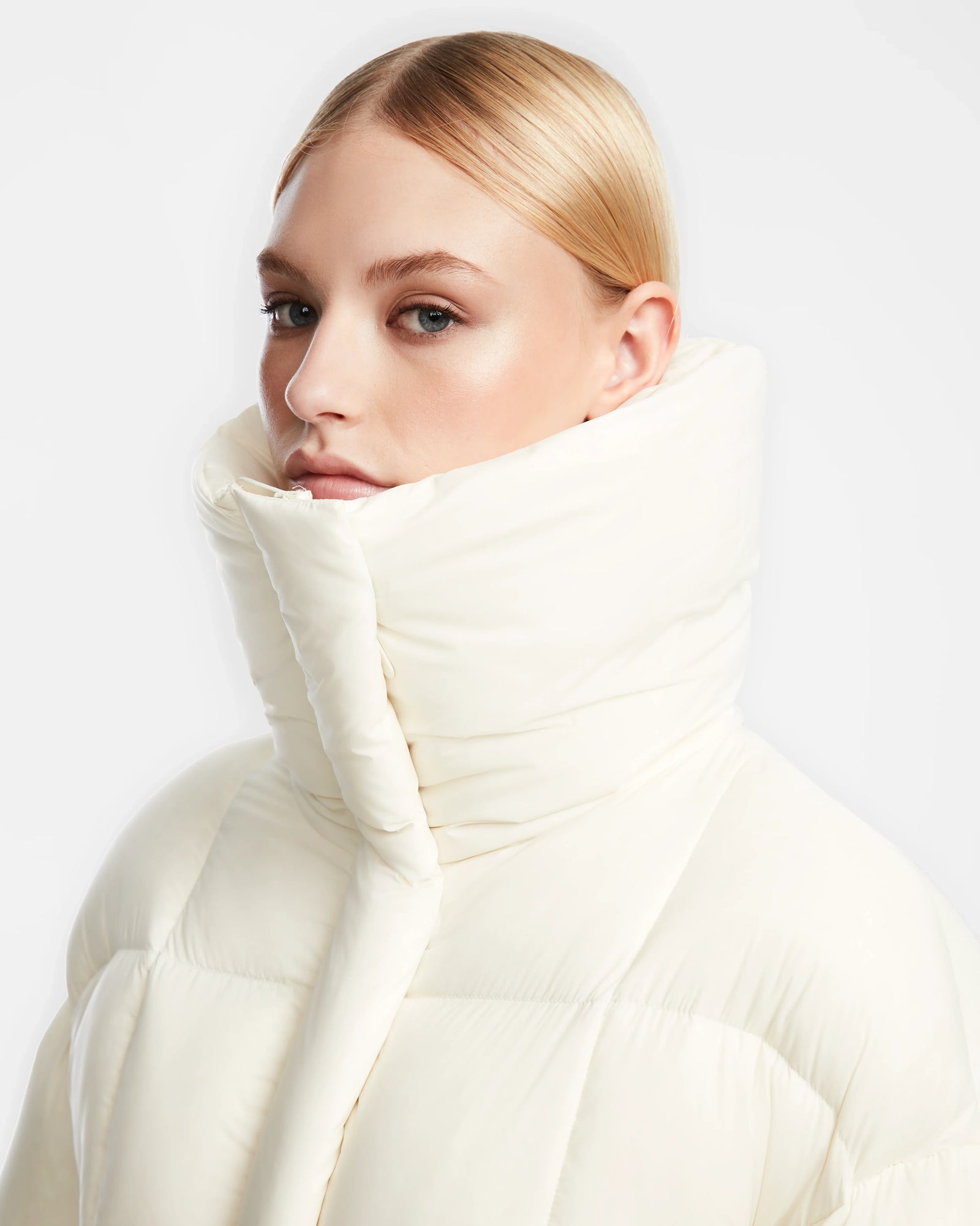 A woman in the Rudsak SASH - 8124536 Iceland womens down puffer coat stands with confidence, ready to conquer winters chill.