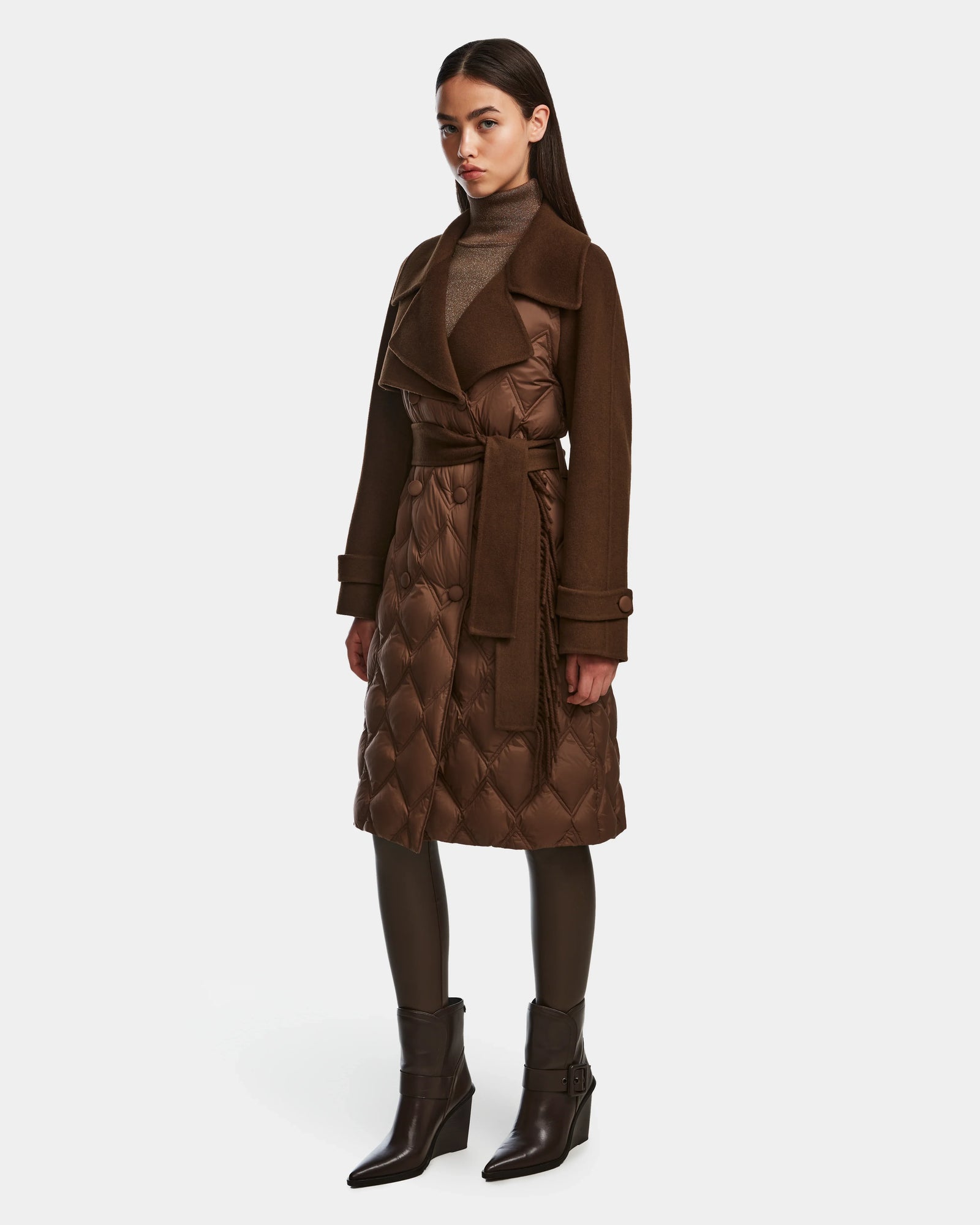 A woman wears the Rudsak ZOE - 8124711 Mocha long dark brown quilted wool trench coat with a wide collar, styled with a brown turtleneck, dark leggings, and brown ankle boots against a light background.