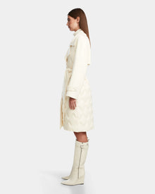 A woman in profile models the Rudsak ZOE - 8124711 Iceland cream belted quilted down trench with matching zippered knee-high boots, set against a plain light background.