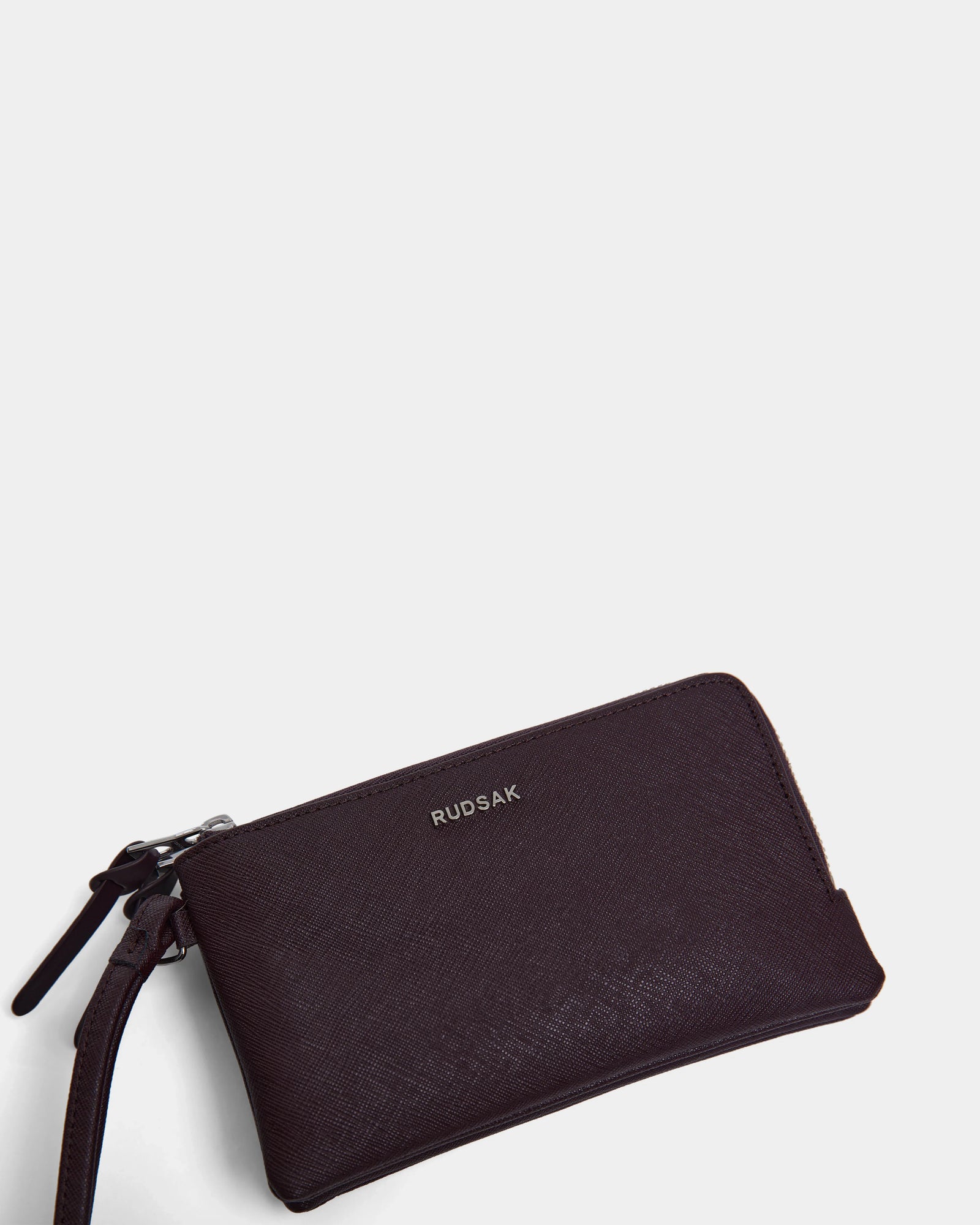 A wine-colored Rudsak ZURIE - L424501 women's leather wristlet wallet with zippered compartments and a wrist strap, displayed on a plain white background.