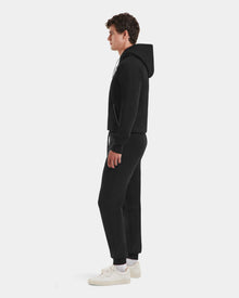A man in profile faces left, wearing the Rudsak MAXTON - U525007 Black M hoodie and joggers for everyday comfort, with white sneakers, set against a plain white background.