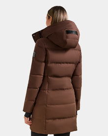 A person is seen from the back wearing the Rudsak MIRIAM - L123544 Mocha women's down puffer coat, featuring a hood, horizontal quilting, an upper-arm patch, and a weather-resistant shell against a plain light background.