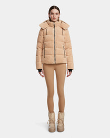 A woman stands facing forward in the Rudsak MIRRY FF - L124507 Iceland tan velvet corduroy puffer jacket with a hood, paired with tan leggings and tan winter boots against a plain white background.