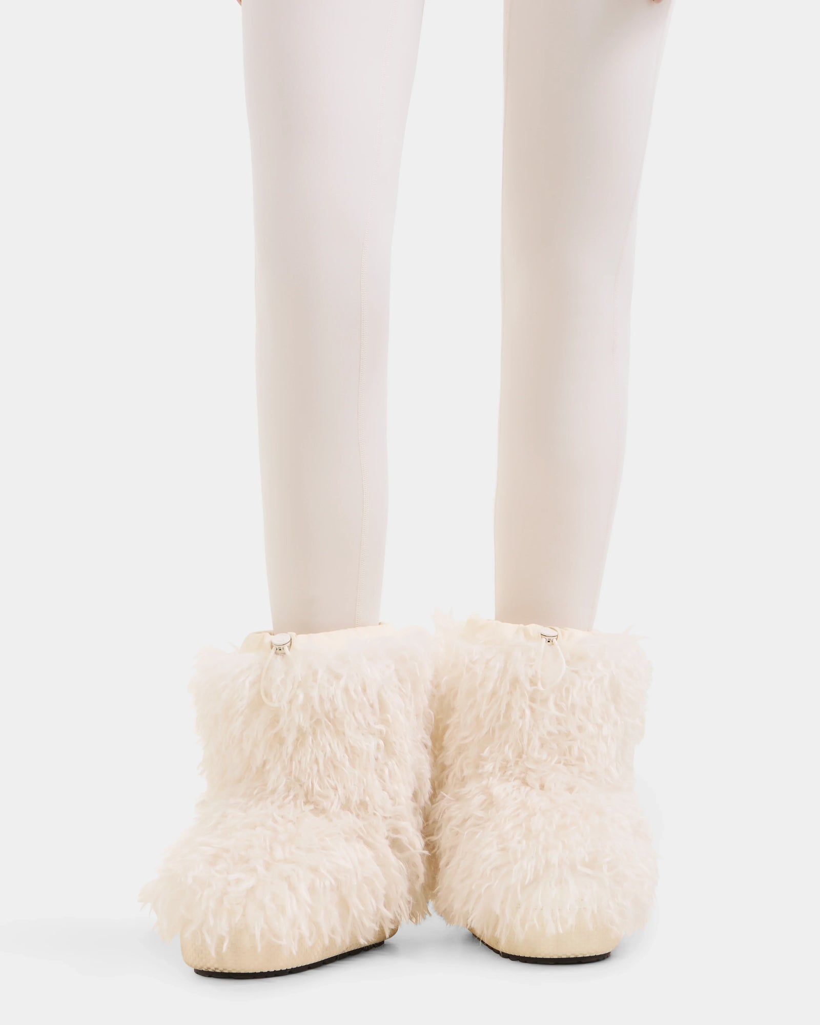 A person in white tights wears Rudsak's ROSSY - 8224518 Iceland fluffy, cream-colored faux Mongolian fur boots, featuring a shaggy texture and cozy look—ideal for women's winter style.