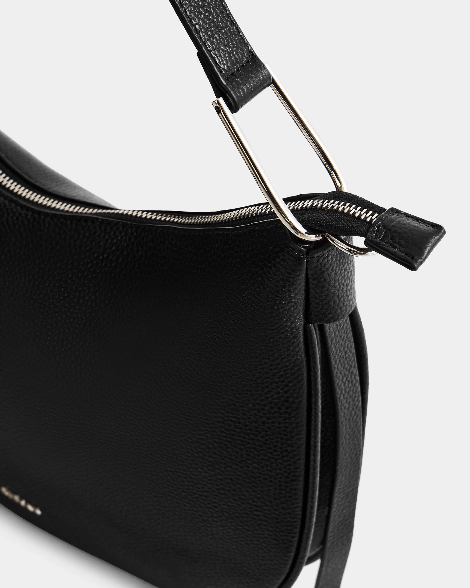 Close-up of the Rudsak SYLVIA - L325515 Black women's shoulder bag in textured leather, featuring a sleek crescent shape, silver zipper, metal hardware, and detailed strap attachment for a modern look.